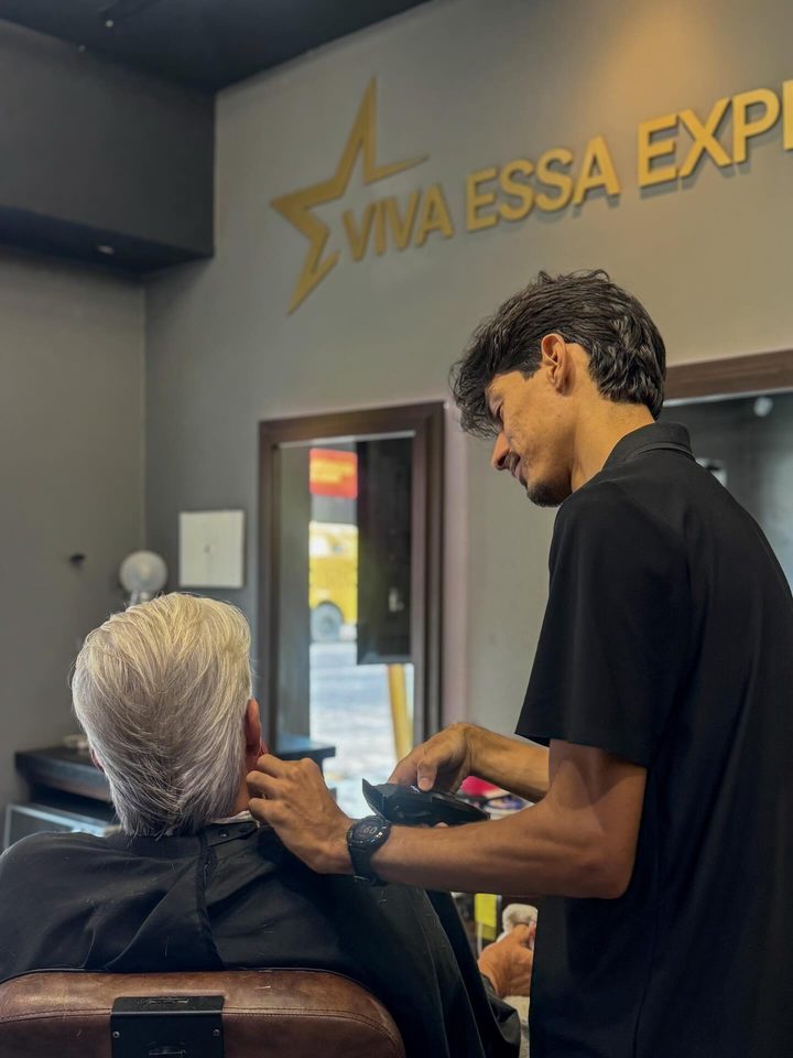 Barbeiro atendendo cliente diante da parede dourada